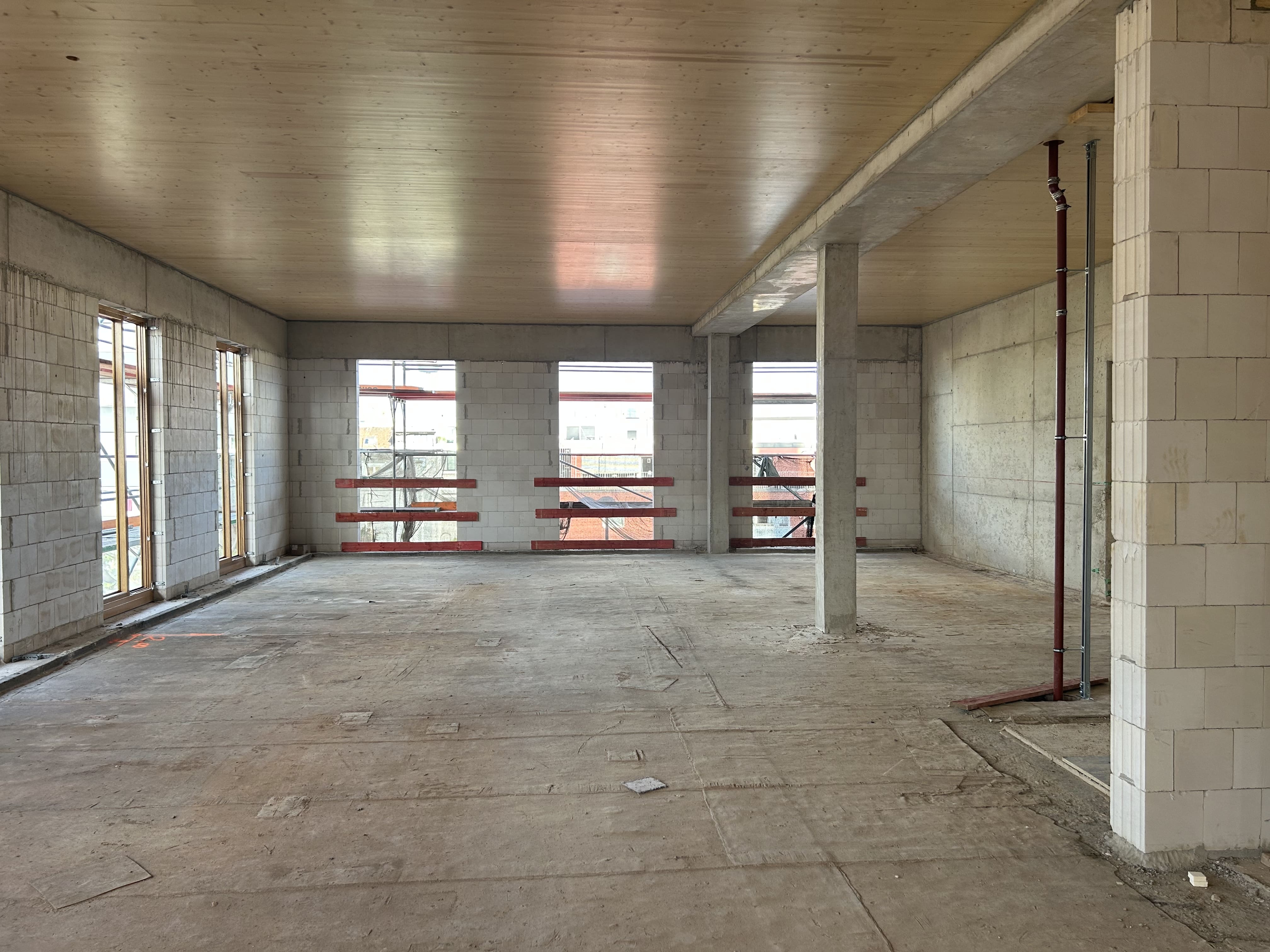 Rohbau-Innenansicht des MACO-Projekts mit Wänden aus Kalksandstein und Holzbalkendecke